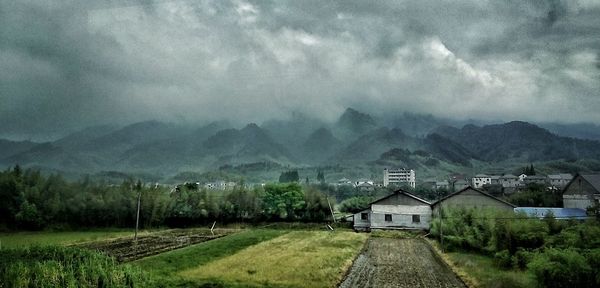 Houses on mountain against cloudy sky