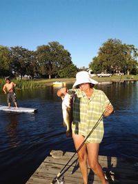 Happy woman holding fish while standing on pier