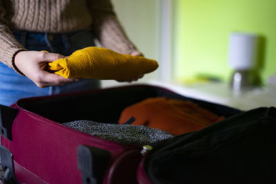 Traveler woman keeping a yellow pullover in the travel suitcase.