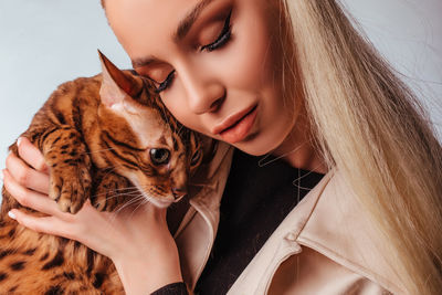 Portrait of an attractive cute young blonde woman with a bengal cat