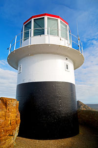 Lighthouse by sea against sky