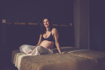 Portrait of smiling young woman sitting on bed