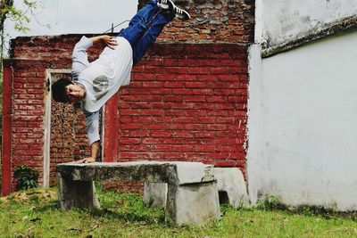 Man practicing stunt on seat in park