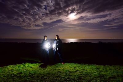 Friends standing field against sky at night