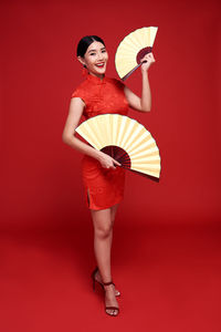 Full length of woman standing against red background