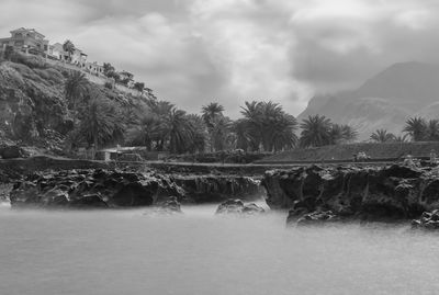 Scenic view of waterfall against cloudy sky