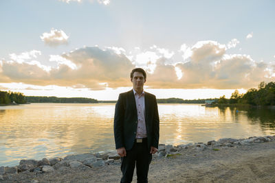 Man standing at beach against sky during sunset