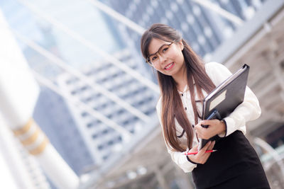 Young businesswoman against building