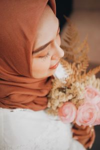Close-up of woman in hijab holding flowering bouquet