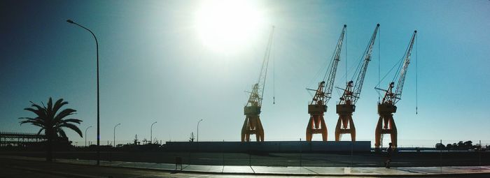 Cranes against clear sky on sunny day