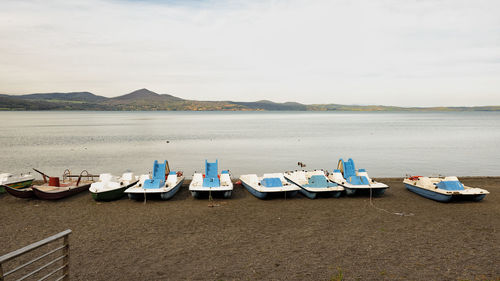 Boats moored on shore against sky