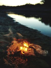 Close-up of bonfire in lake at sunset