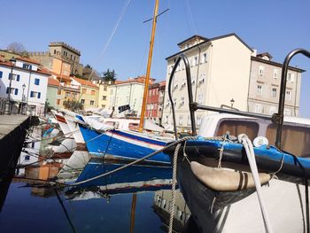 Boats moored at harbor against clear blue sky