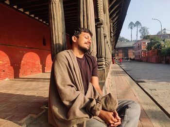 Portrait of young man sitting on street