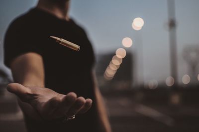 Midsection of man levitating bullet at dusk