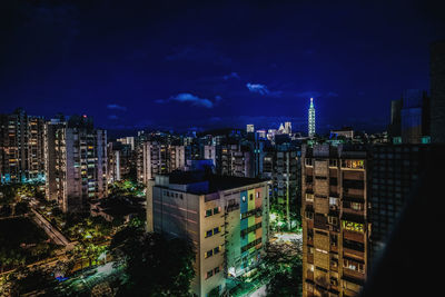 Illuminated buildings in city against sky at night