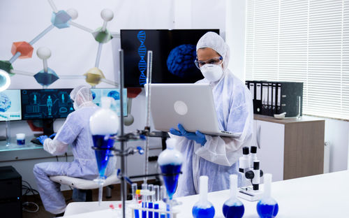 Scientist using laptop standing in laboratory