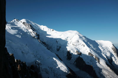 Scenic view of snowcapped mountains against clear blue sky