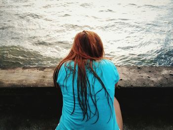 Rear view of woman sitting against sea
