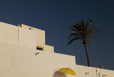 Low angle view of palm tree and white building against blue sky in las negras, almeria, spain