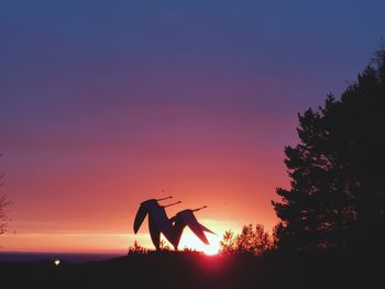 Silhouette people standing by tree against sky during sunset