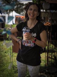Smiling young woman drinking glass while standing outdoors
