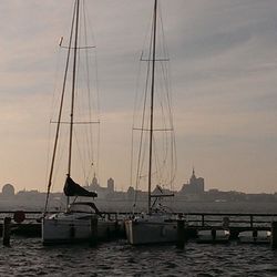 Sailboats in sea at sunset