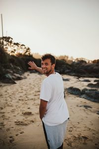 Young man standing on beach against sky