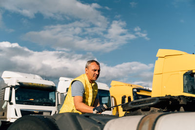 Low angle view of man standing on car against sky