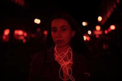 Portrait of young woman standing on road at night