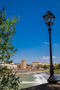 Street light by building against blue sky