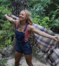 High angle view of happy woman holding shawl in forest