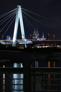 Illuminated bridge over river against sky at night