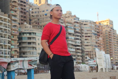 Full length of young man standing against buildings in city