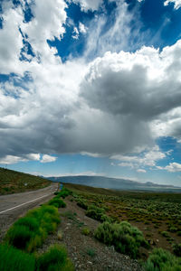 Road amidst field against sky