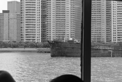 Reflection of person on river against buildings in city