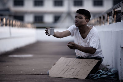 Young man sitting on street in city