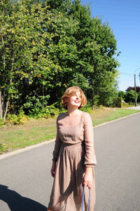 Young caucasian girl walks with two dogs on the road among tall trees in summer