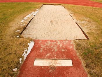 Lane for the long jump. sandy red retrack, white ake-off board. poor grass around.