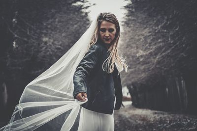 Portrait of beautiful woman standing against trees