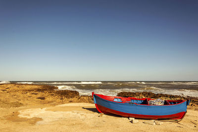 Boat moored on beach against clear sky