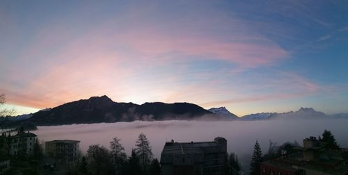 Panoramic view of buildings and mountains against sky during sunset