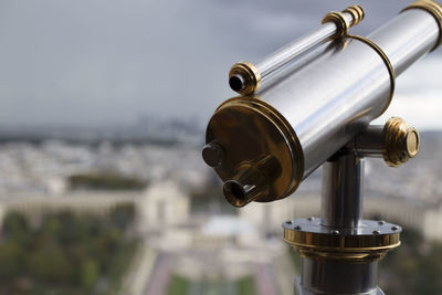 Close-up of coin-operated binoculars against cityscape