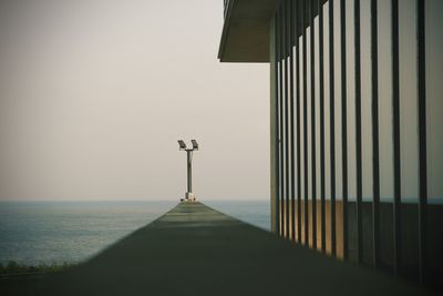 Low angle view of street light on pier against sea and sky