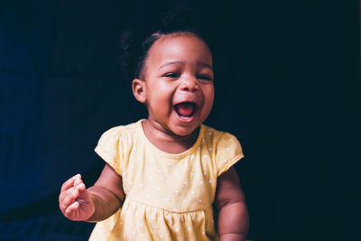 Portrait of cute smiling boy against black background