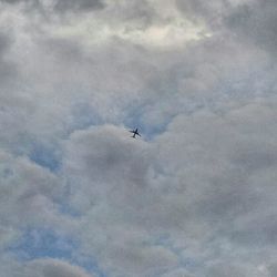 Low angle view of helicopter flying against cloudy sky