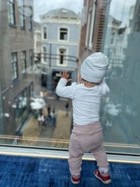Toddler looking out of the glas front to the the urban city of den haag