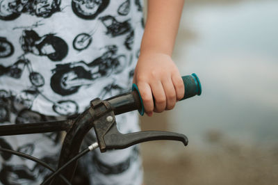 Midsection of child holding bicycle