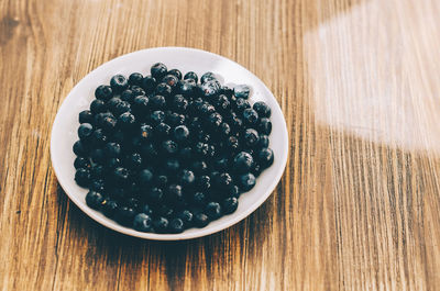 High angle view of blueberries in plate on wooden table