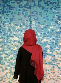 Rear view of woman in traditional clothing against blue patterned wall